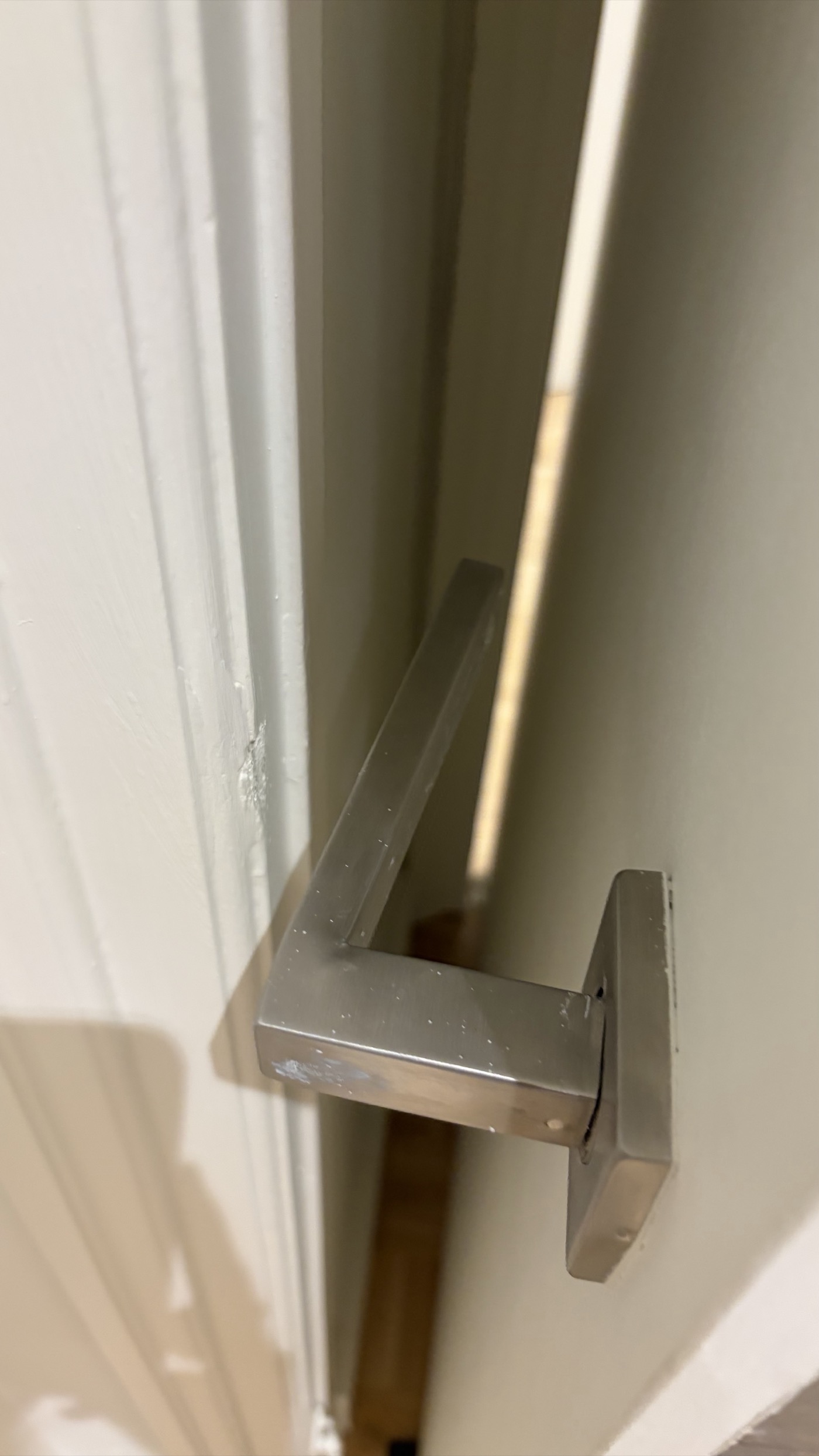 Door handle lever visibly bent upward from years of hitting the wall