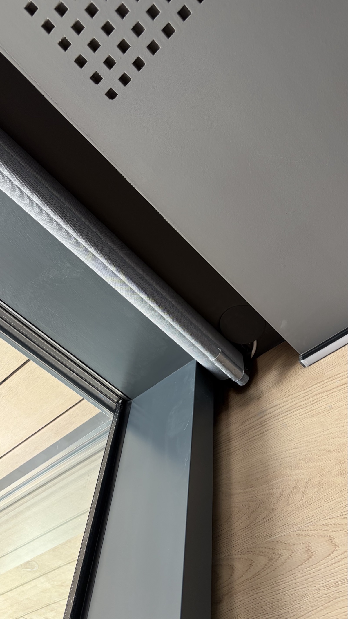 Motorized roller blind mounted to ceiling with side guides along window frame