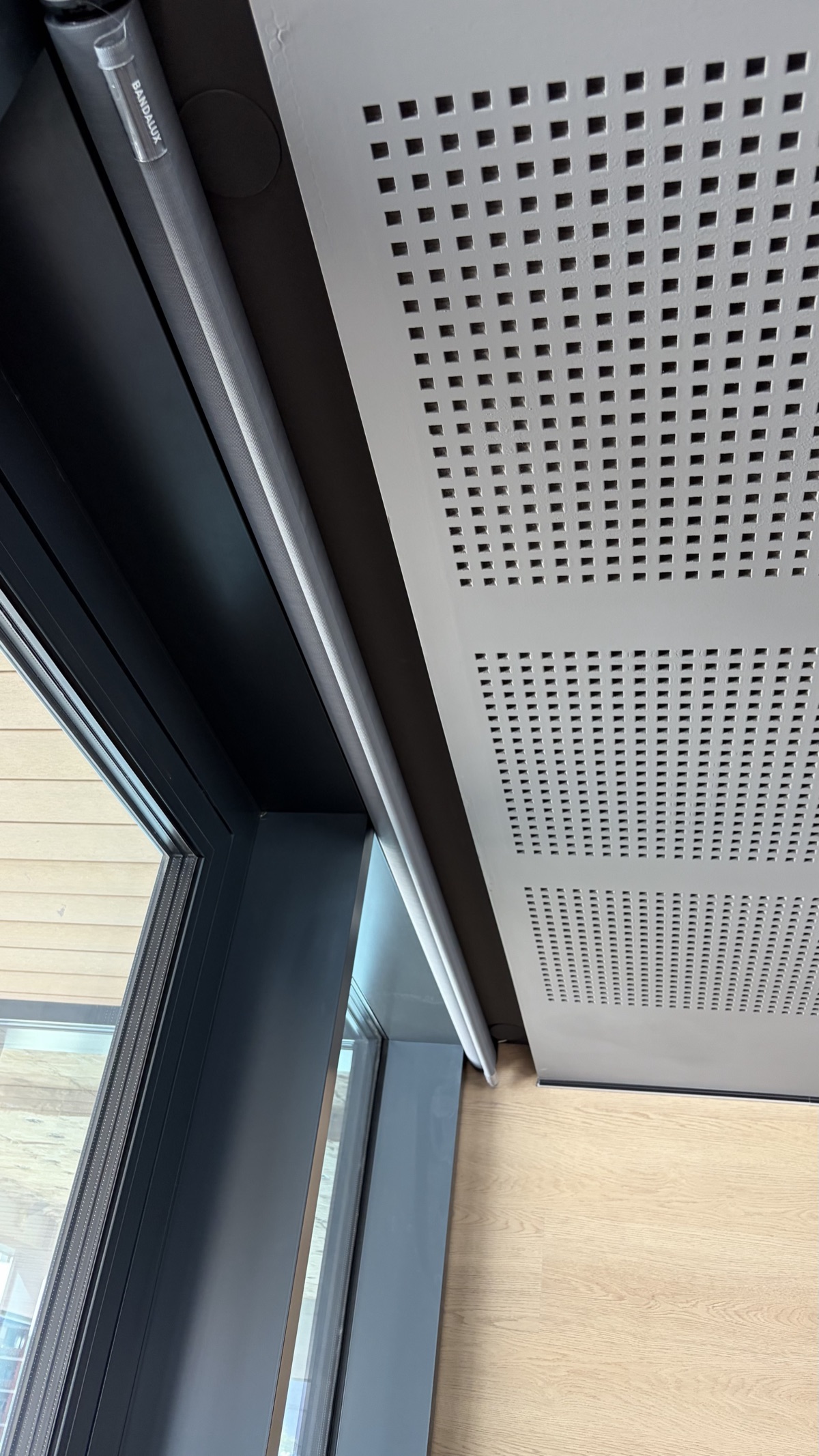 Close-up of motorized roller blind motor housing showing brand label and wiring channel