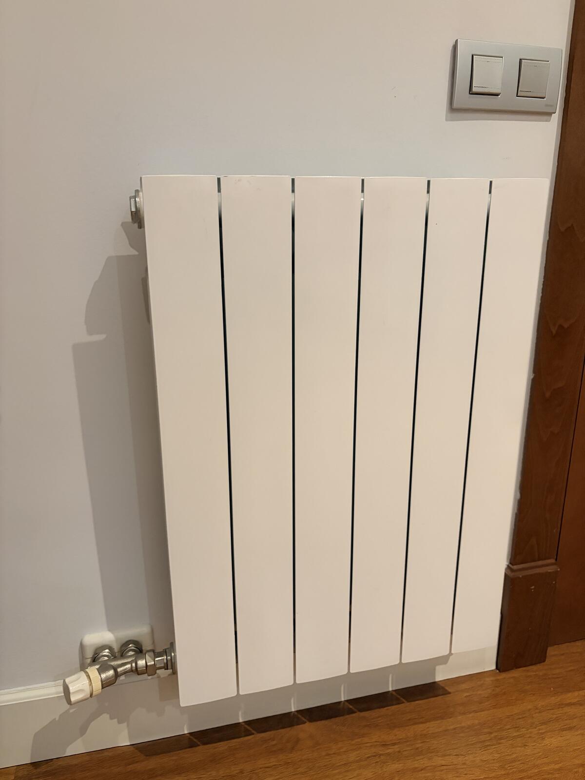 Close-up of a radiator bleed valve at the top corner of a hot water radiator