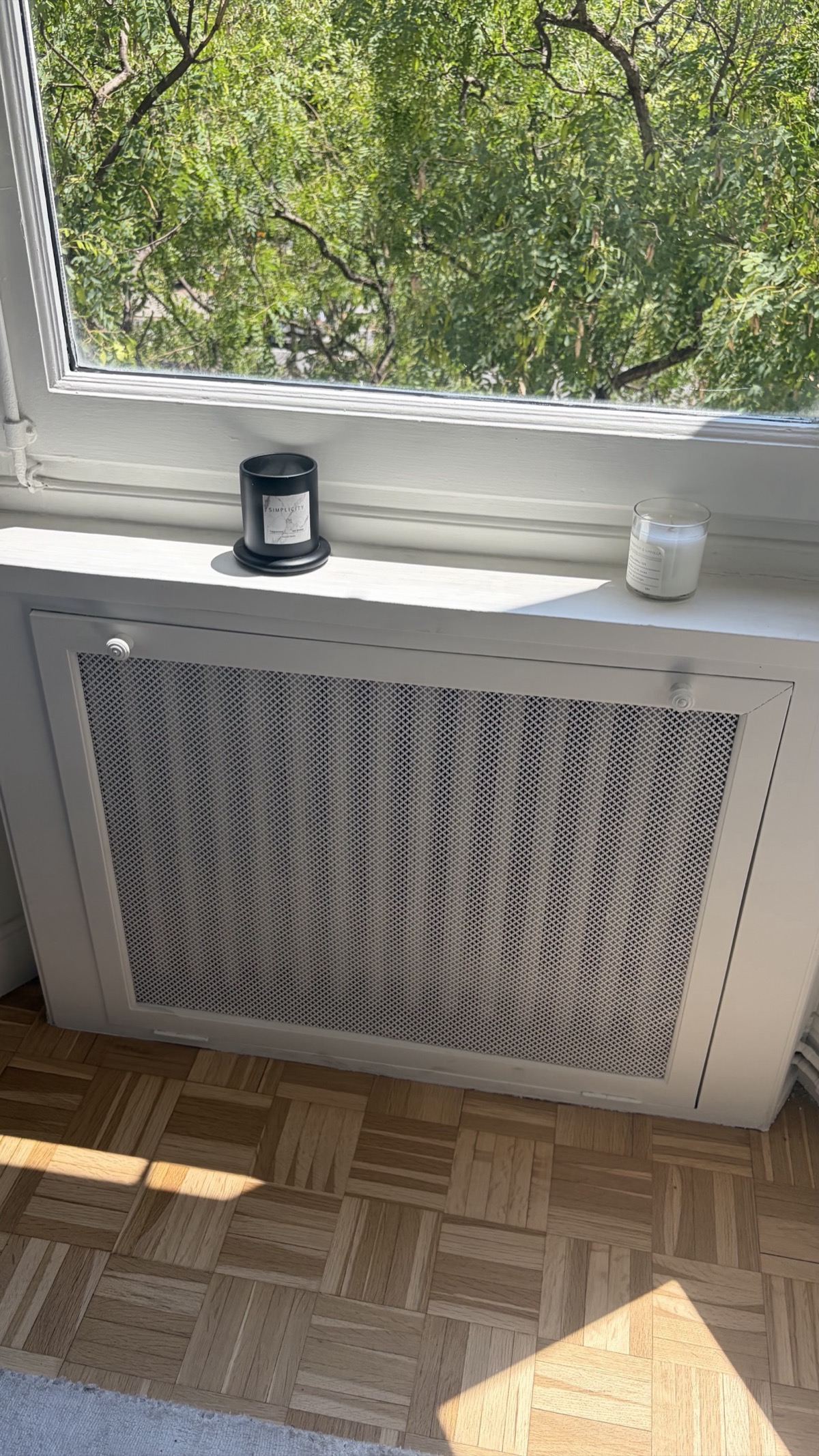 Repaired radiator cover with mesh grille sitting flush under a window